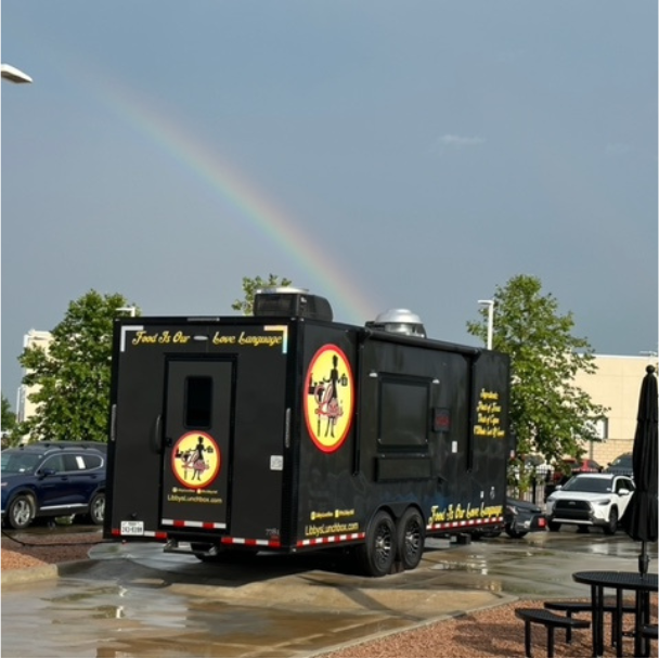 Food truck with rainbow behind it.